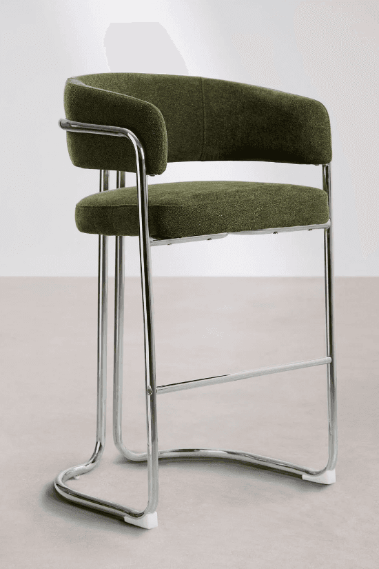 A tall bar stool featuring a bent tubular chrome frame and upholstered seat and backrest. The frame forms a continuous loop creating a sled base and supports the seat and back. The seat and back are cushioned and covered in a textured olive green fabric, with the back curving around to form integrated armrests. A horizontal chrome bar serves as a footrest. The design reflects a modernist aesthetic. — 3D model