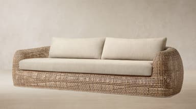 A contemporary sofa featuring a curved, open-weave rattan frame and soft, light-colored upholstered cushions on the seat and back. — 3D model