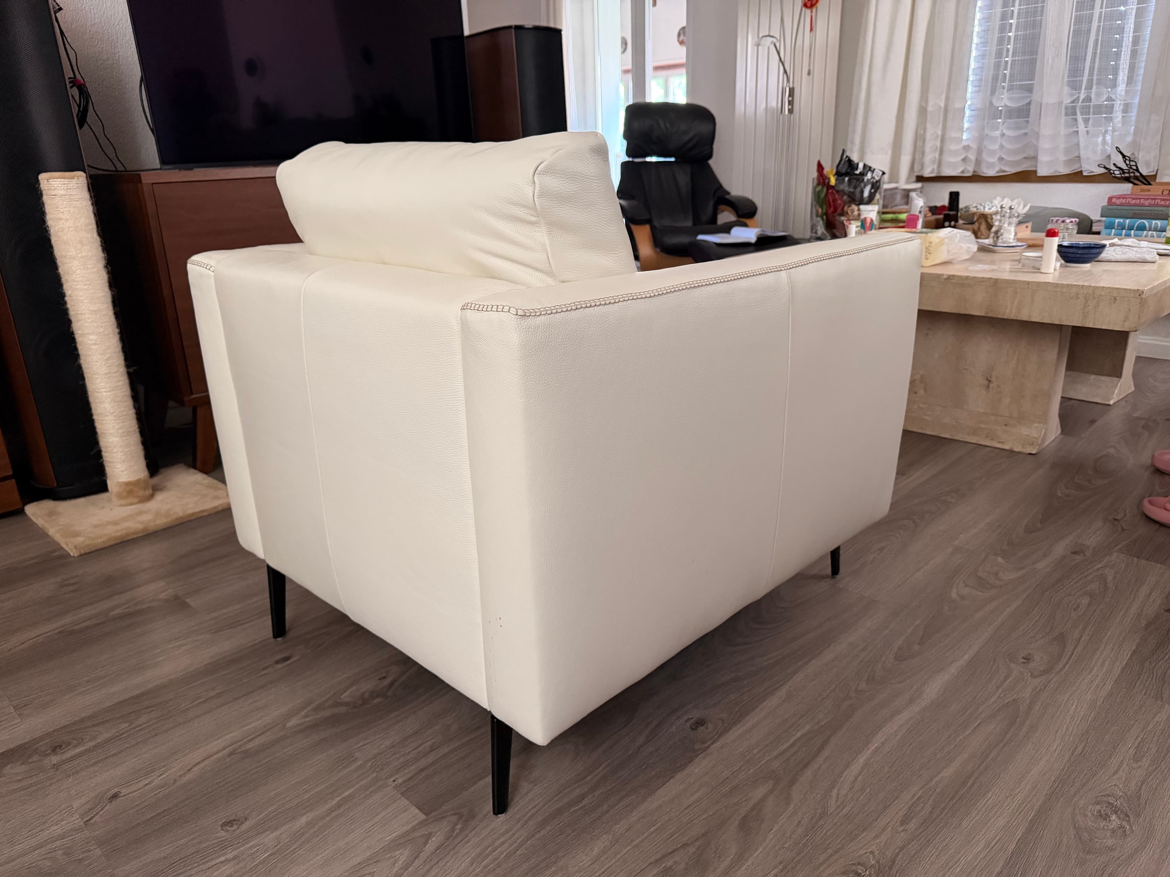 A modern white sofa with a tufted backrest and armrests, upholstered in a material that appears to be faux leather or high-quality vinyl. It features a clean, minimalist design with slim, black metal legs. The stitching detail is visible along the edges. — 3D model