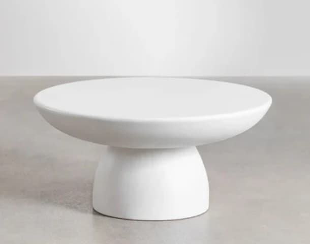 A modern round coffee table featuring a smooth, matte white finish and a substantial pedestal base, creating a minimalist and sculptural aesthetic. — 3D model