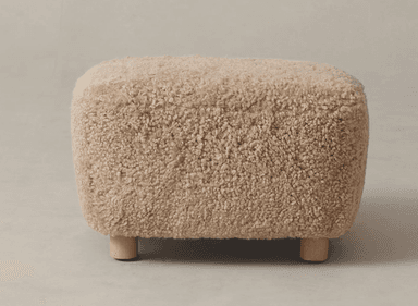 A rectangular ottoman with rounded edges, covered in a textured, fluffy, off-white material resembling sheepskin. It is supported by four short, cylindrical wooden legs. — 3D model