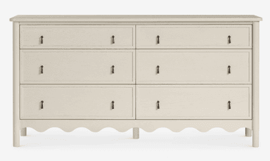 A contemporary light gray double dresser featuring six drawers, arranged in two columns of three. The bottom edge of the dresser has a distinctive scalloped design, and each drawer is fitted with a simple, dark-toned pull handle. The dresser stands on four rounded legs, and its top surface has softly rounded corners. — 3D model