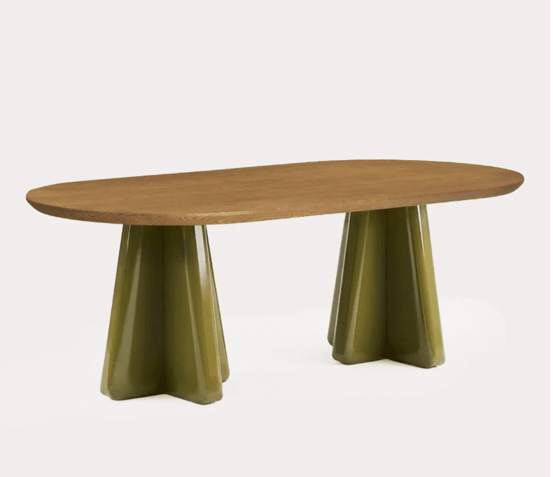 An oval dining table featuring a natural wood top and two distinctive olive green lacquered pedestal bases. Each base is sculptural, fluted, and tapered, ending in a four-point star-like foot. The overall design is contemporary and sleek. — 3D model