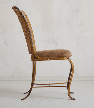 A vintage chair with a woven wicker back and a padded seat. The frame appears to be made of metal and is painted yellow with visible stitch-like detailing. The legs are curved and provide a decorative, elegant stance. The backrest has a distinctive shape, widening towards the top with curved accents. — 3D model