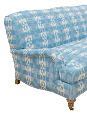 A detailed view of the side and back of a light blue and white patterned sofa. The upholstery features a plaid-like design with interspersed geometric motifs. The sofa has rounded arms and is supported by wooden legs, one of which is visible with turned detailing and a small wheel. — 3D model