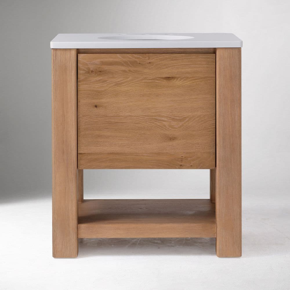 A modern, freestanding bathroom vanity featuring a light-toned oak wood frame and body, topped with a clean white integrated sink and countertop. The design includes a large, full-width drawer and an open lower shelf for additional storage or display. The natural wood grain is prominent, and the overall aesthetic is clean and minimalist. — 3D model