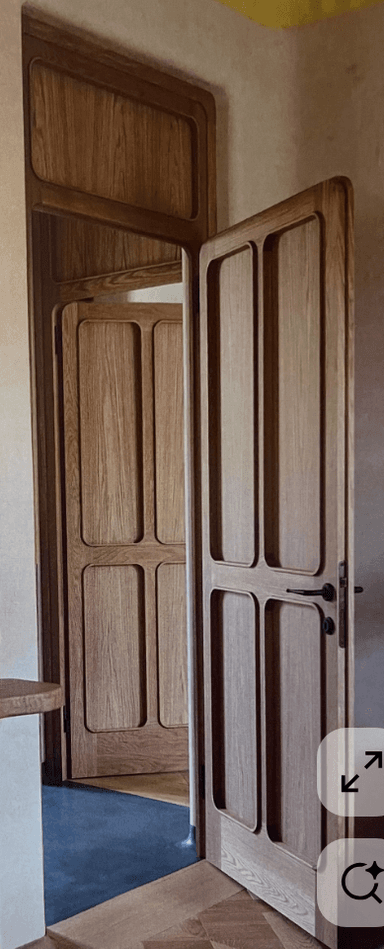 A single interior door with a natural wood grain finish. The door features a paneled design with two rectangular recessed panels on the upper section and two similar panels on the lower section, separated by a horizontal rail. The edges of the door have a rounded profile. A black metal door handle with a lever mechanism is attached to the right side of the door, indicating it is hinged from the left when viewed from this perspective. — 3D model
