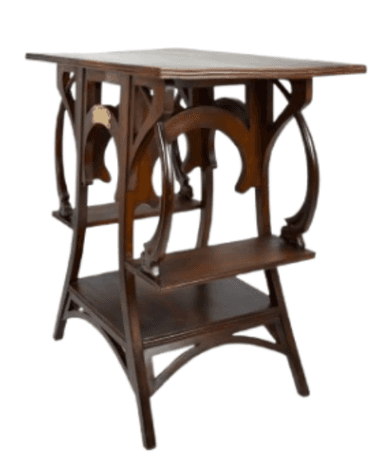 A dark wooden accent table with a rectangular top and two lower shelves. The table features ornate, curved wooden supports that create an open, sculptural base. A small, decorative brass plaque is affixed to one of the central supports. — 3D model
