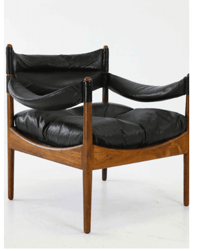 A mid-century modern armchair with a wooden frame and black leather upholstery. The chair features a distinctive curved backrest and armrests, with a thick, cushioned seat. The wooden frame is composed of four tapered legs and a supporting structure that cradles the seat and backrest. The leather appears to be of good quality, with some visible creasing and texture. — 3D model
