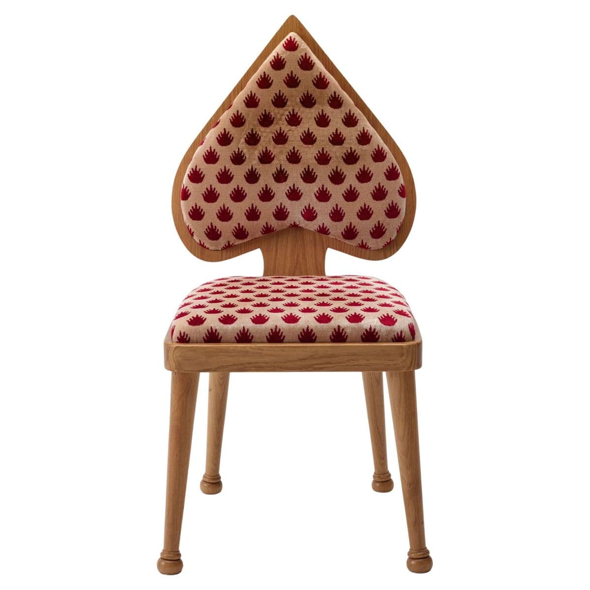 A uniquely shaped accent chair with a backrest and seat upholstered in a fabric featuring a repeating pattern of small red spade emblems on a light beige background. The frame and legs are made of light-colored wood. The backrest is shaped like a spade from a deck of cards, with the upholstered portion forming the main body of the spade, bordered by a wooden frame. The seat is rectangular and also upholstered. The chair has four tapered legs that end in rounded feet. — 3D model