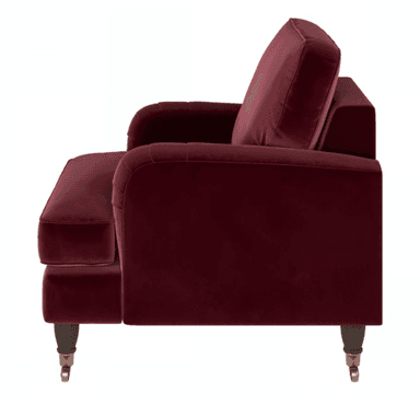 A deep red, velvet upholstered armchair featuring rolled arms with subtle pleating, a plush seat cushion, and dark turned wooden legs with brass casters. — 3D model