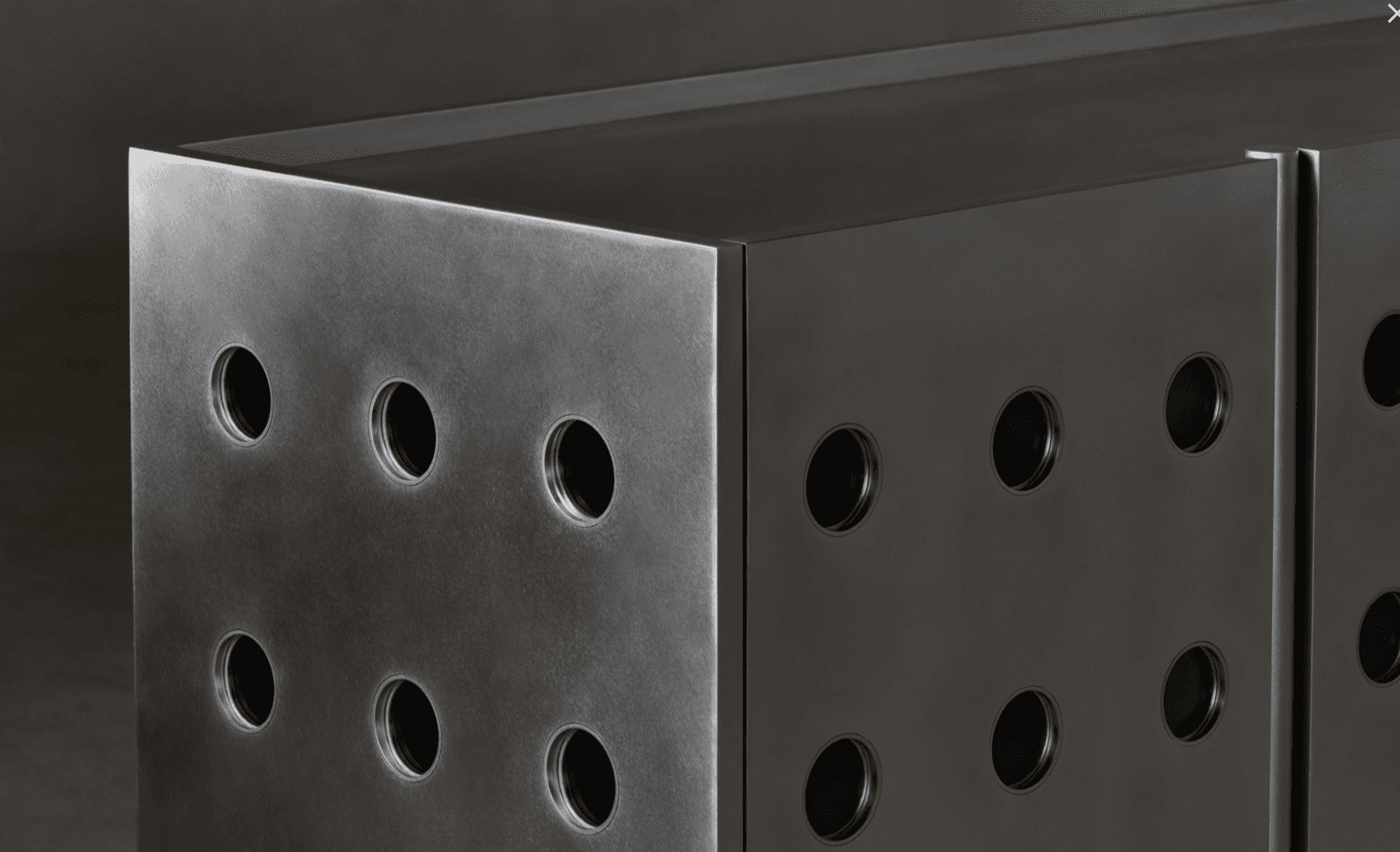 A modern cabinet with a brushed metal finish, featuring a series of circular cutouts on its visible face. The design is minimalist and geometric, suggesting a contemporary or industrial aesthetic. The surface exhibits a brushed texture, and the circular openings appear to be evenly spaced. — 3D model