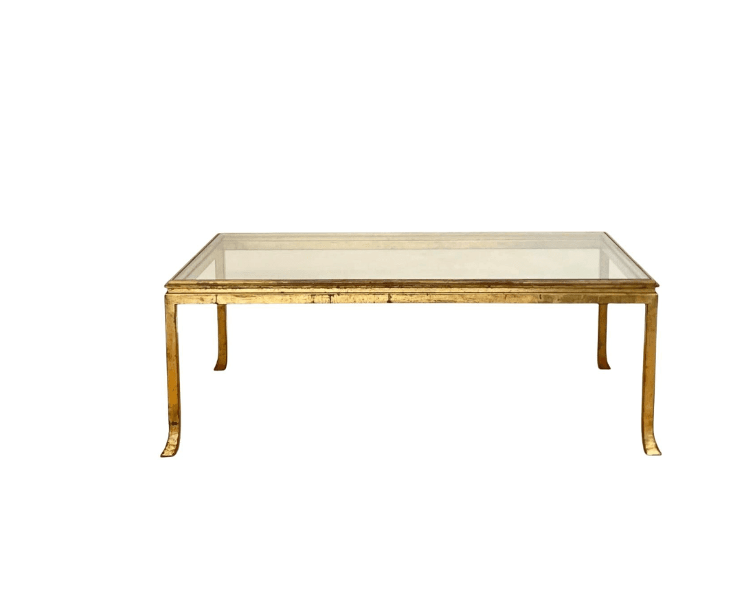 A rectangular coffee table with a clear glass top and a gold-toned metal frame. The frame has a distressed finish, and the legs have a subtle curve at the bottom. — 3D model