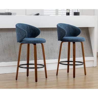 A modern bar stool featuring a blue fabric upholstered seat and a curved backrest that functions as partial armrests, supported by splayed dark wooden legs with a black metal footrest ring, and a swivel mechanism. — 3D model