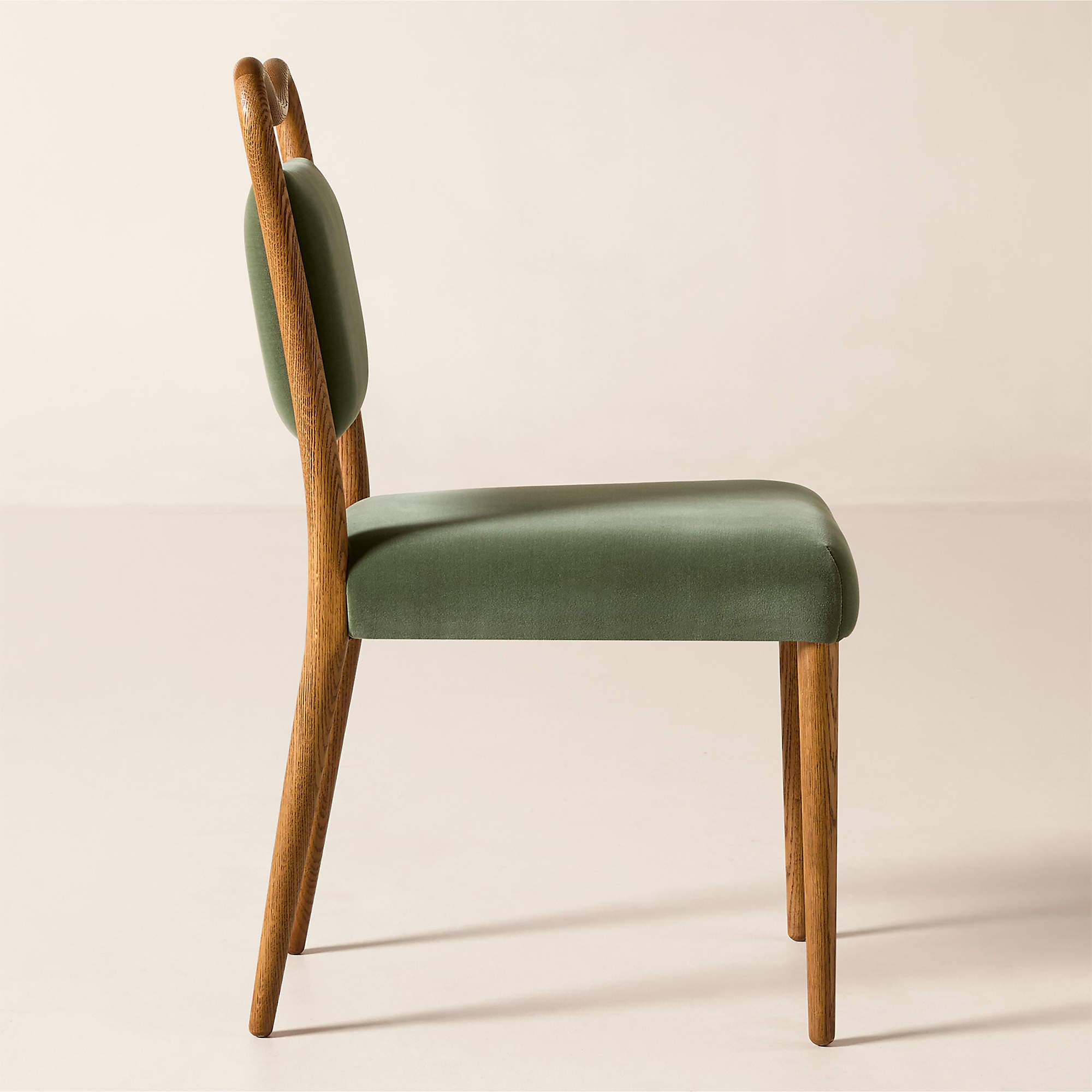 A side profile view of a modern dining chair featuring a wooden frame and upholstered seat and backrest. The chair has a curved wooden back support and four tapered wooden legs. The seat and back are covered in a soft, matte green fabric. — 3D model