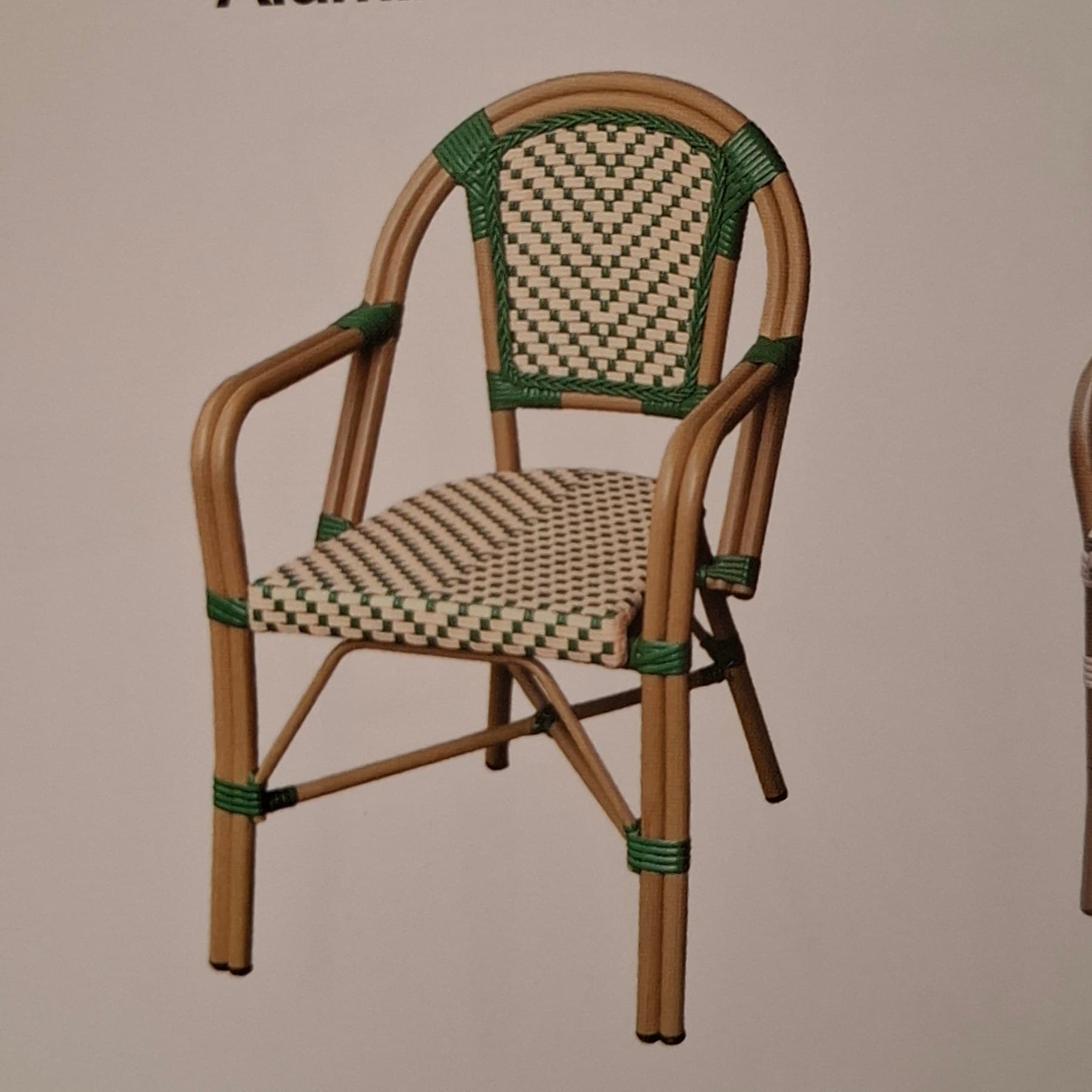 A light brown and green wicker armchair with a curved back and armrests. The seat and back are woven in a checkerboard pattern, alternating between light beige and green. The frame appears to be made of bent bamboo or rattan, with green wicker bindings at various joints. The chair has four legs, connected by crossbars for stability. It is designed for outdoor or bistro use. — 3D model