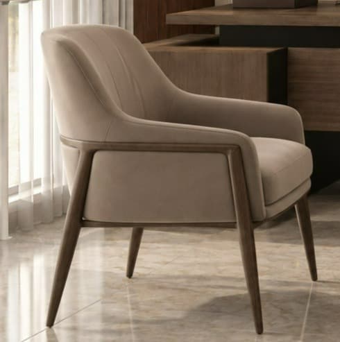 A modern upholstered accent armchair featuring a minimalist design. The chair has a comfortable, well-padded seat, backrest, and arms, all covered in a smooth, light beige or taupe fabric. The backrest is subtly adorned with vertical stitching, adding a refined detail. A dark wood frame is exposed along the outer edges of the arms and forms the sturdy, tapered legs, providing a contemporary contrast to the upholstery. — 3D model