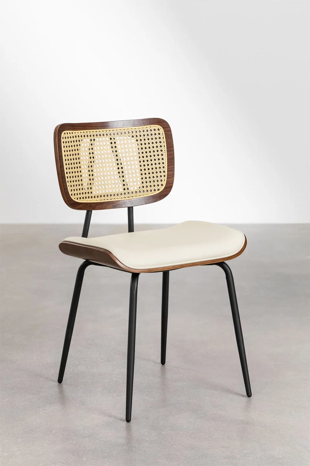 A contemporary dining chair featuring a curved dark wood frame with a woven cane backrest, an upholstered off-white seat, and slender black metal legs. — 3D model
