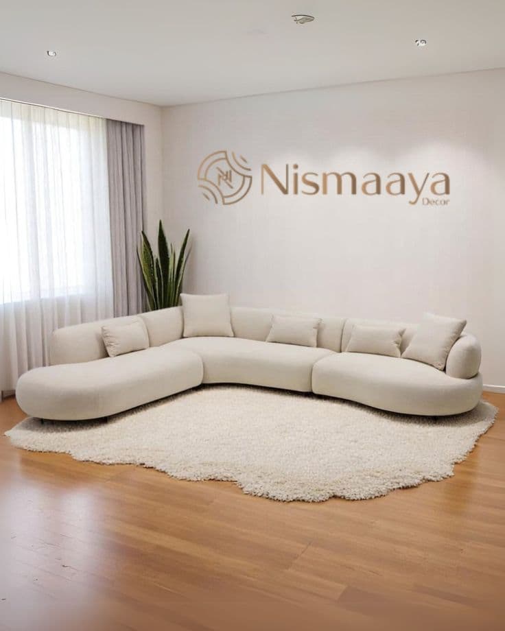 A large, low-profile, curved modular sectional sofa upholstered in a light-colored fabric, arranged in a sweeping 'S' shape on a plush rug in a modern living space. — 3D model