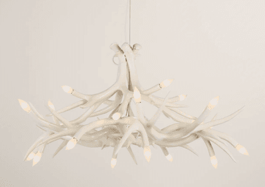 A white chandelier designed to resemble a cluster of antlers. It features multiple branching elements that curve and intertwine, with small, flame-shaped bulbs positioned at the ends of many of these branches, providing illumination. The overall form mimics natural antler growth patterns, creating a rustic yet sophisticated aesthetic. — 3D model