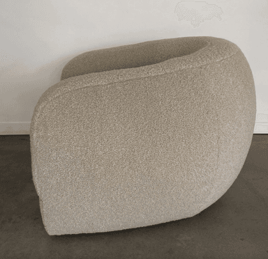 A rounded armchair with a plush, textured upholstery. The armchair features a deep seat and a wraparound backrest that seamlessly integrates into the armrests. The texture appears to be a boucle or similar looped fabric, giving it a soft and inviting appearance. — 3D model