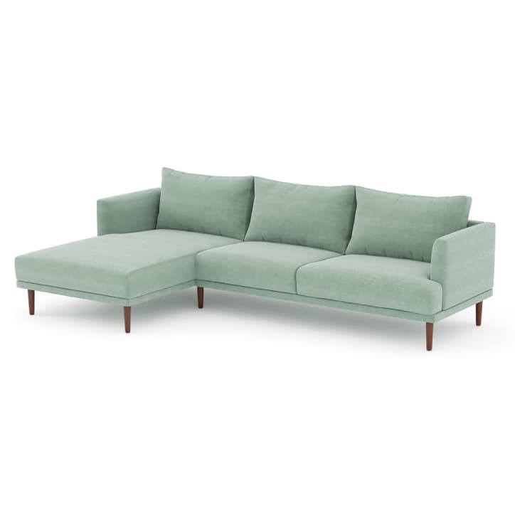 A modern L-shaped sectional sofa featuring a chaise lounge on the left, upholstered in a light green fabric, and supported by slender wooden legs. — 3D model