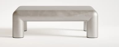 A contemporary coffee table with a monolithic design. It features a rectangular top with rounded edges that seamlessly transitions into four cylindrical legs. The overall form is smooth and sculptural, suggesting a modern aesthetic. — 3D model