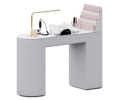 A modern manicure station featuring a white and light grey finish with a faux marble tabletop. The desk is supported by a curved, fluted leg on the left and a rectangular cabinet-style leg on the right, which incorporates an integrated nail polish display rack. It is equipped with a gold-finished task lamp, a nail drill, and a UV curing lamp, making it a complete setup for professional nail services. — 3D model