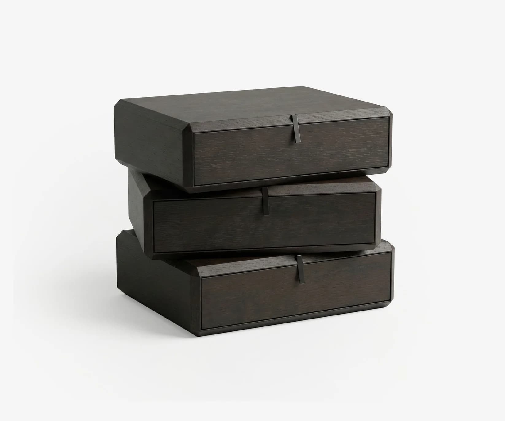 A set of three dark-stained wooden storage modules, stacked in an offset, dynamic arrangement. Each module features a single drawer with a flush face and an integrated recessed pull handle. The units have subtly chamfered or angled edges, contributing to a modern, geometric aesthetic. — 3D model