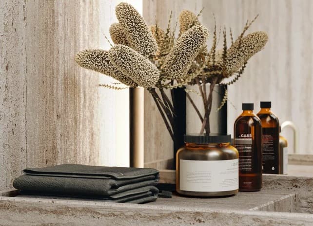 A minimalist decorative arrangement featuring a matte black ceramic vase holding several stems of dried pampas grass. The vase has a simple, cylindrical form with a narrow opening, and the dried grass has a feathery, beige-brown texture, creating an organic, contemporary aesthetic. — 3D model