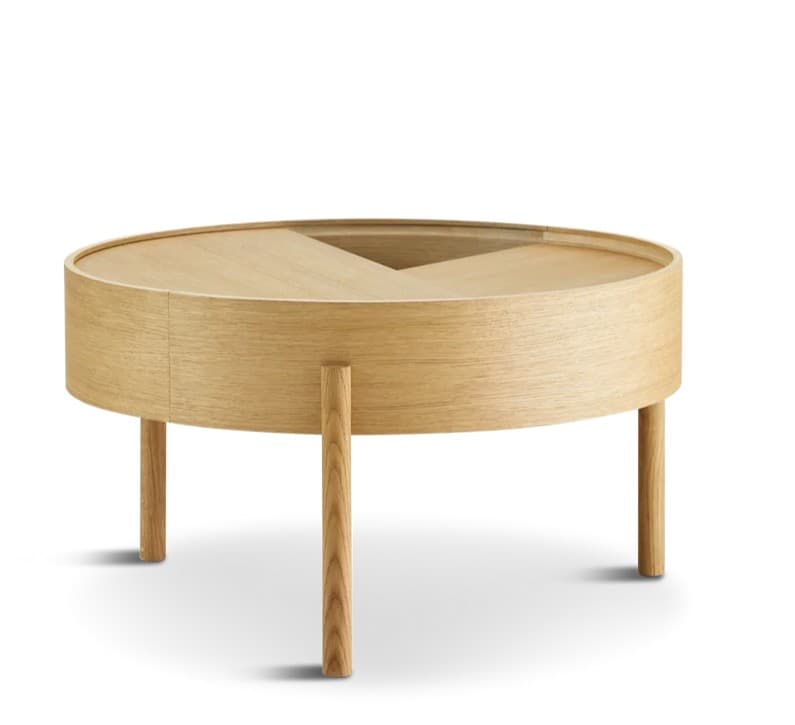 A modern circular coffee table crafted from light-toned wood, featuring a unique top with segments that pivot or slide to reveal internal storage compartments. It is supported by four solid cylindrical wooden legs, presenting a minimalist aesthetic. — 3D model