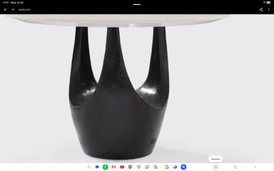 A contemporary dining table featuring a round white tabletop supported by a distinctive dark, sculptural pedestal base with multiple organic lobes. — 3D model