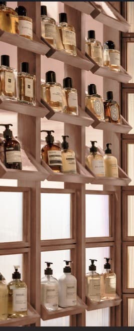 A wooden shelving unit with multiple angled shelves designed to display bottles. The unit has a light wood finish and appears to be free-standing. — 3D model