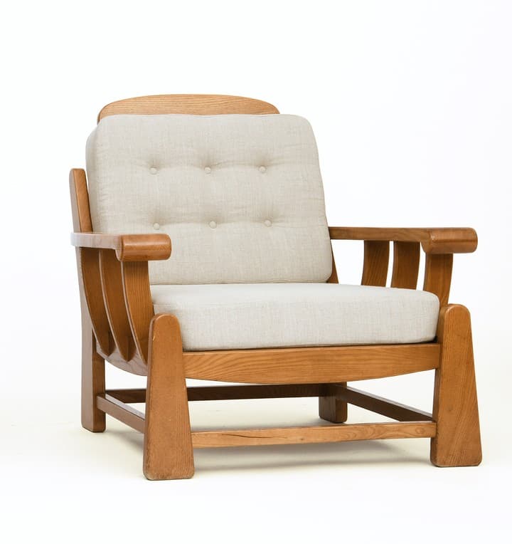 A sturdy, craftsman-style lounge chair featuring a solid oak wood frame and thick, upholstered cushions. The chair has broad, rounded arms, slatted side panels, and block legs. The back cushion is button-tufted. — 3D model