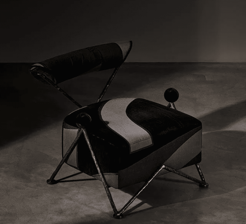 An Art Deco-inspired lounge chair featuring a plush upholstered seat and backrest, supported by an intricate copper-finished metal frame. The upholstery showcases a geometric pattern with sections of black and grey velvet, creating a dynamic visual. The frame incorporates hammered texture and distinctive spherical accents at the front corners of the seat and supporting the backrest. — 3D model
