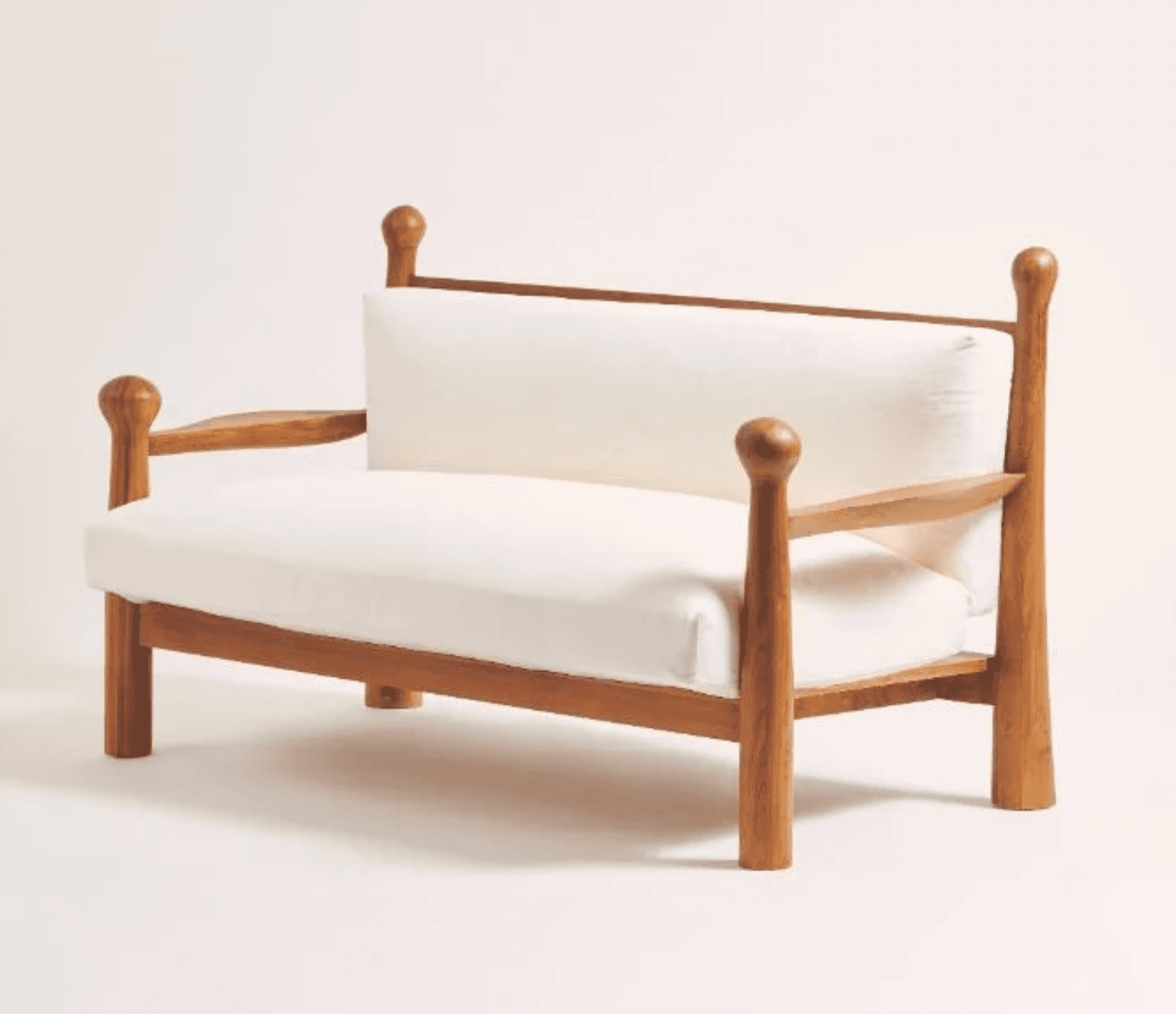 A wooden loveseat featuring a solid wood frame with distinctive turned posts at each corner, topped with spherical finials. It includes thick, removable seat and back cushions upholstered in white fabric. The armrests are open slats, and the entire piece rests on sturdy, straight legs. — 3D model