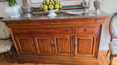 A wooden sideboard with a marble top. It features multiple drawers and cabinet doors with metal hardware. The wood has a warm, medium-brown finish. The marble top has a speckled, grey and brown pattern. The piece has a traditional or classic style, indicated by the paneling on the doors and the molding details. — 3D model