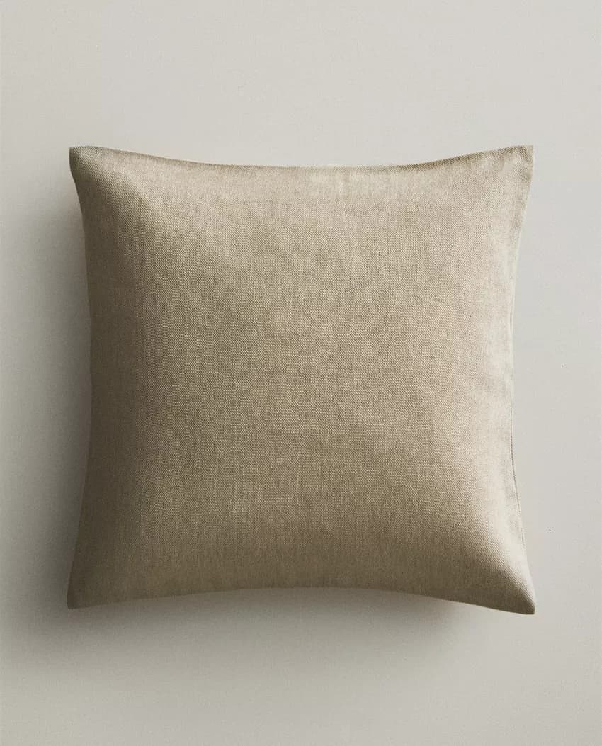 A square-shaped cushion with a textured, woven surface. The edges are softly rounded, indicating a filled interior. The fabric appears to be a natural fiber, possibly linen or a linen blend. — 3D model