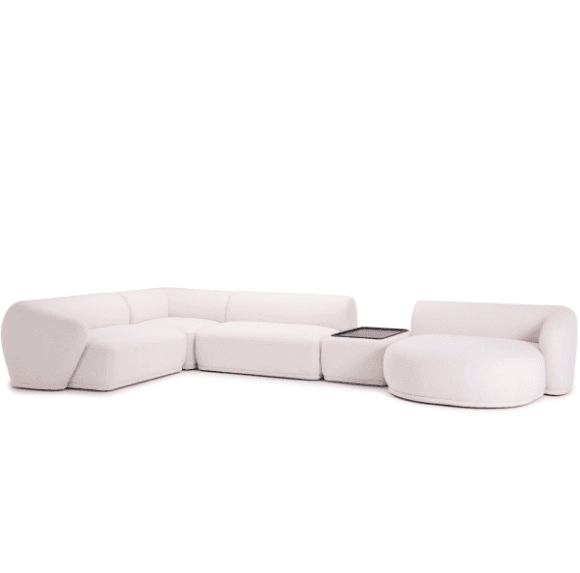 A white sectional sofa with a modular design, consisting of multiple pieces that can be arranged in different configurations. It features a curved, rounded shape and a low profile. The sofa is upholstered in a smooth, light-colored fabric. There is also a small table with a black glass top integrated into the sectional. The sofa appears to be new and in excellent condition.