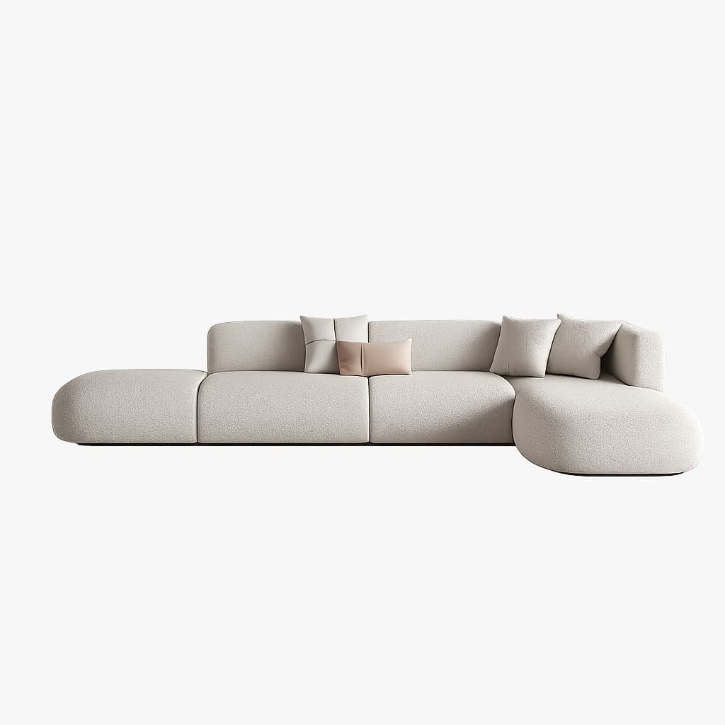 A modern modular sectional sofa upholstered in a light beige bouclé fabric. It features a low-profile design with generously rounded edges and deep, plush seating, consisting of an armless central section, a corner unit, and a spacious chaise lounge extension. Several throw pillows are placed on the sofa. — 3D model