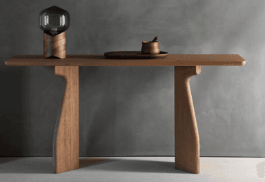 A minimalist wooden bench crafted from light-colored wood, likely oak or ash, featuring a rectangular top with subtly rounded edges. The bench is supported by two distinctively shaped, thick slab legs that are positioned inward from the ends, providing a stable and sculptural base. The overall aesthetic is clean and contemporary. — 3D model