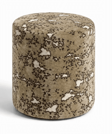 A fully upholstered, cylindrical ottoman featuring a distinctive digital camouflage pattern in shades of beige, brown, and off-white. The piece has a soft, plush texture, suggesting a velvet or similar pile fabric. Its round top and consistent diameter give it a clean, modern form. — 3D model