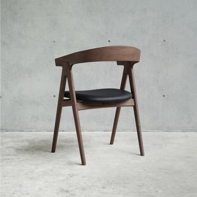 A modern armchair with a curved wooden frame and a black upholstered seat. The chair has four angled legs, a curved backrest that extends into armrests, and a distinctively shaped seat. — 3D model