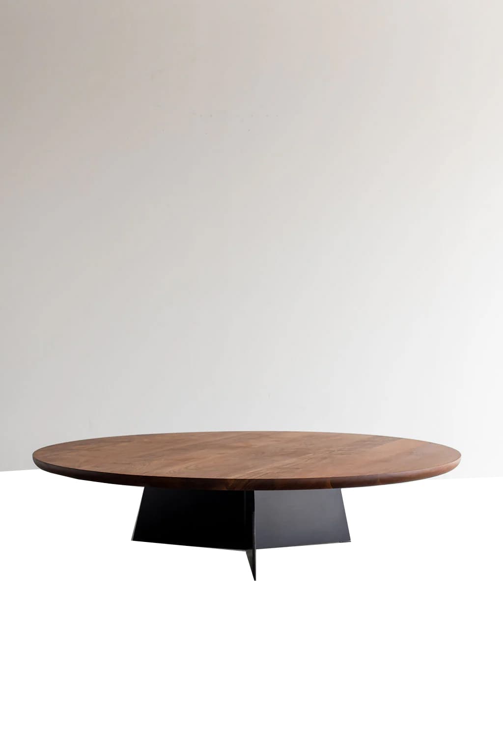 A modern coffee table with an oval-shaped wooden top and a distinctive geometric metal base. The tabletop exhibits a natural wood grain pattern. The base is angular and appears to be constructed from dark, possibly black, metal with four legs that taper to sharp points. — 3D model