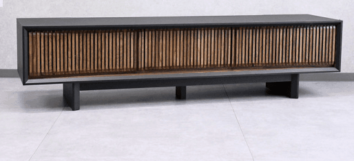 A long, low credenza featuring a slatted wooden front and a dark, matte frame. The credenza is supported by two rectangular, dark-colored legs. The front has a ribbed texture due to the vertical wooden slats, which are varied in color from light brown to a deeper golden hue. The top and sides of the credenza are a solid dark color, likely black or charcoal gray. — 3D model