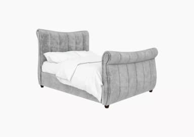 A contemporary upholstered sleigh bed frame featuring a gracefully curved headboard and footboard, both adorned with vertical channel tufting. The entire frame is covered in a soft, grey textured fabric, likely velvet or a similar material. The bed is designed with a low profile, supported by short, dark wooden legs. A white duvet and pillows are visible on the mattress, indicating its function. — 3D model
