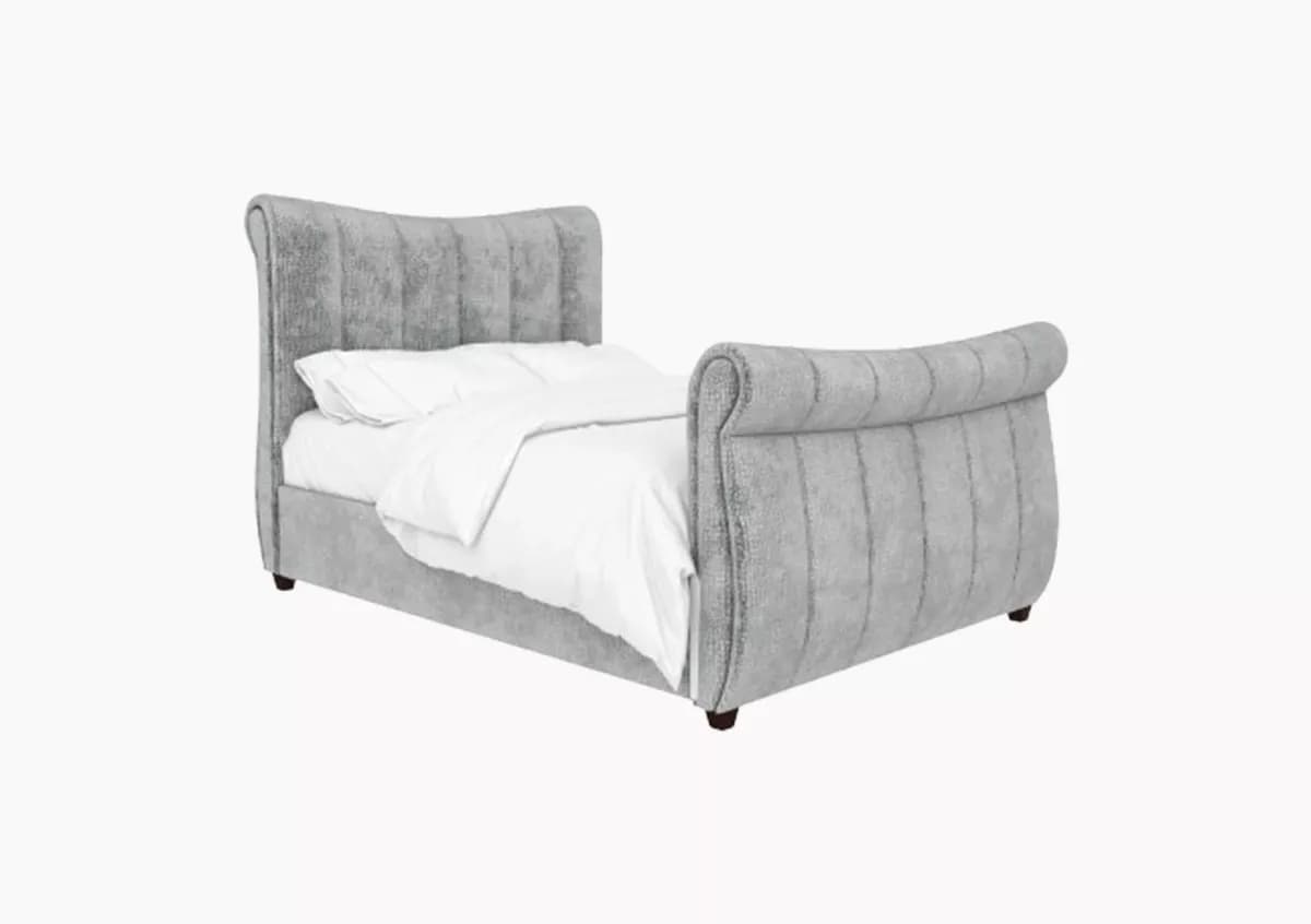 A contemporary upholstered sleigh bed frame featuring a gracefully curved headboard and footboard, both adorned with vertical channel tufting. The entire frame is covered in a soft, grey textured fabric, likely velvet or a similar material. The bed is designed with a low profile, supported by short, dark wooden legs. A white duvet and pillows are visible on the mattress, indicating its function. — 3D model