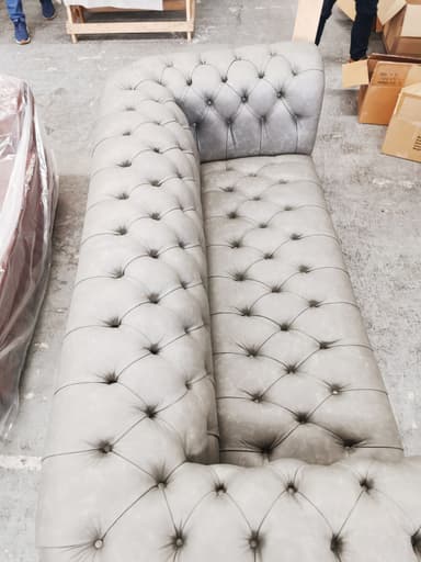 A classic Chesterfield sofa upholstered in a light grey leather-look material, featuring deep button tufting across the backrest, rolled arms, and the front apron. It has a continuous single seat cushion. — 3D model