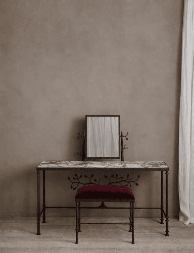 A decorative vanity set consisting of a dressing table with a marble top and a matching upholstered stool, both featuring dark metal frames with botanical scrollwork and an adjustable mirror. — 3D model