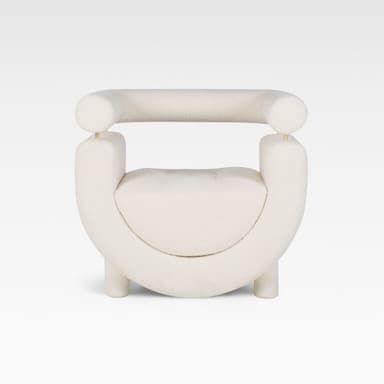 A contemporary cream-colored accent chair featuring a distinctive U-shaped upholstered body with a separate, cylindrical backrest/armrest element supported by thin brass rods. The chair is upholstered in a soft boucle fabric and stands on short, cylindrical upholstered legs. — 3D model